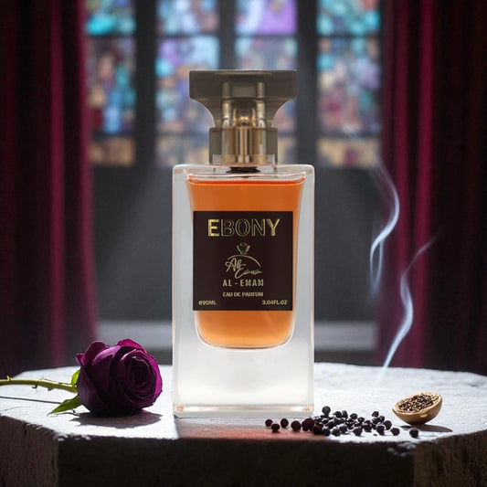 Perfume bottle labeled 'Ebony' by Al-Ham on a table with a purple rose and spices, against a stained glass window background.
